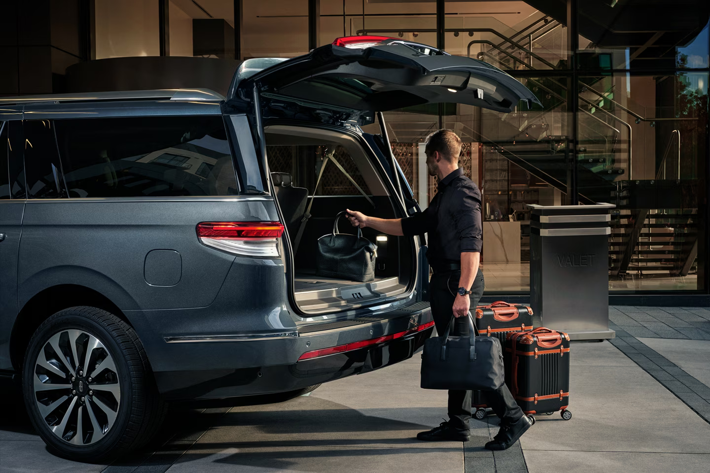 Chauffeur assisting a customer by loading luggage into a luxury SUV in Taxi Worcester